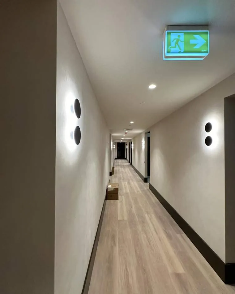 Commercial corridor with wall lights and illuminated emergency exit sign